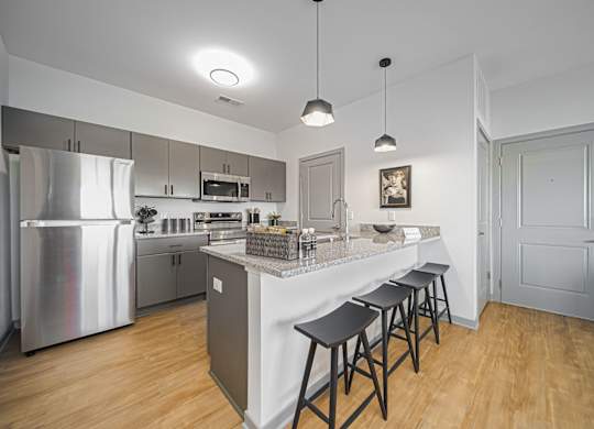 A kitchen with a refrigerator, stove, and bar stools.