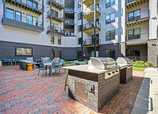 A brick BBQ grill is in the middle of a patio.