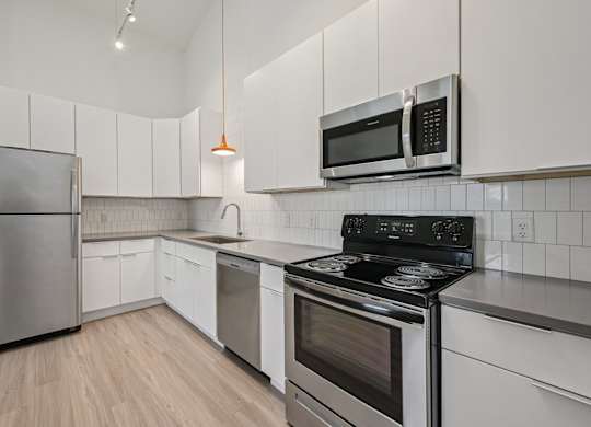 A kitchen with a stove, microwave, and refrigerator.