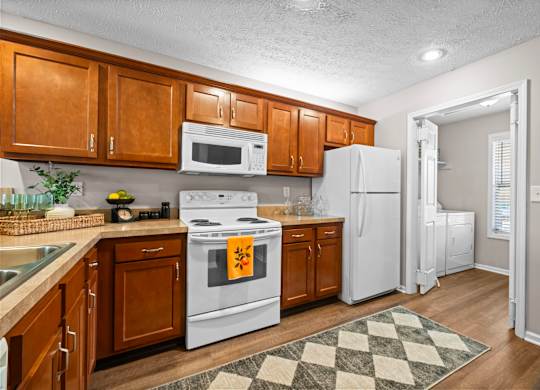 A kitchen with white appliances and wooden cabinets.
