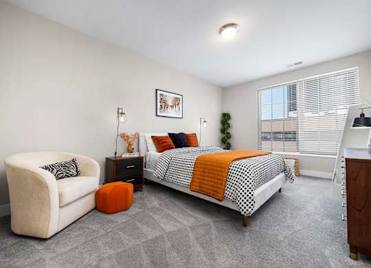 A bedroom with a bed, chair, and nightstand.