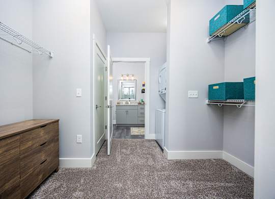 a walk in closet with a mirrored closet door and a bathroom in the background