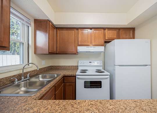 A kitchen with a stove, sink, and refrigerator.