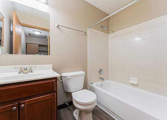 A white toilet sits next to a white bathtub in a bathroom.