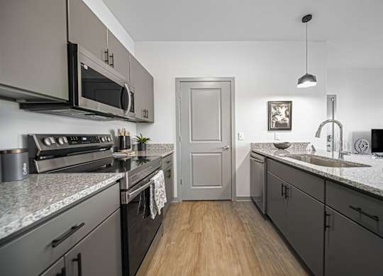 A kitchen with a grey theme and a wooden floor.