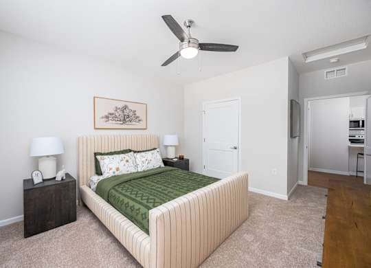 A bedroom with a bed, nightstands, and a ceiling fan.