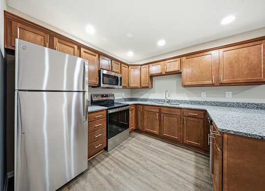 A kitchen with a stainless steel refrigerator and wooden cabinets.