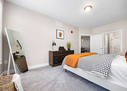 A bedroom with a bed, dresser, and mirror.
