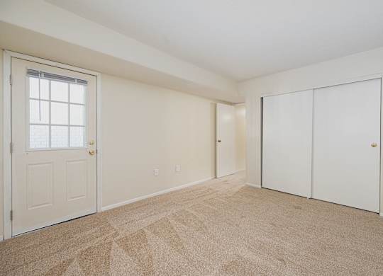 an empty living room with a door to a closet