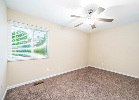 an empty room with a window and a ceiling fan