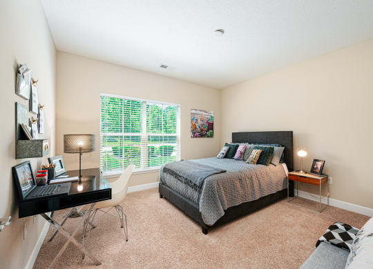 a bedroom with a bed and a desk and a window