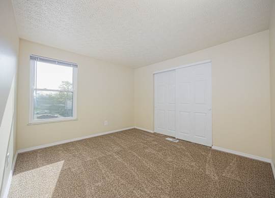 A room with a white door and carpeted floor.