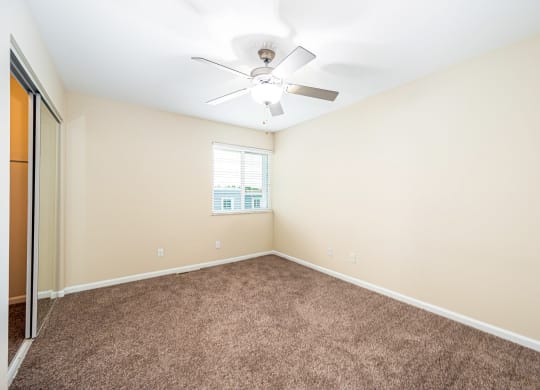 an empty room with carpet and a ceiling fan