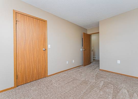 A room with a carpeted floor and two doors.