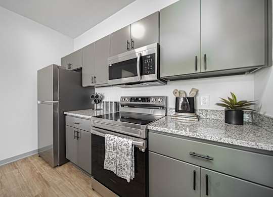 A modern kitchen with stainless steel appliances and a wooden floor.