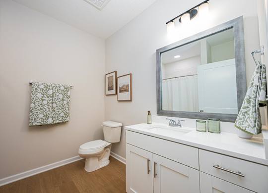 A white bathroom with a toilet, sink, and mirror.