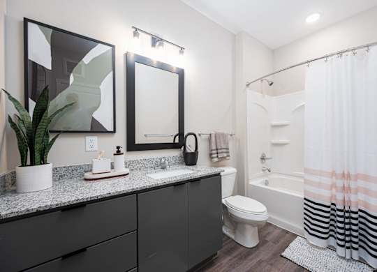A bathroom with a toilet, sink, mirror, and shower.