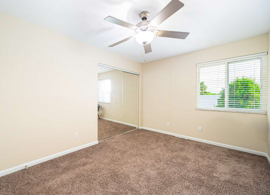 an empty living room with a ceiling fan and a window