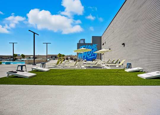 A pool area with lounge chairs and a large mural on the wall.