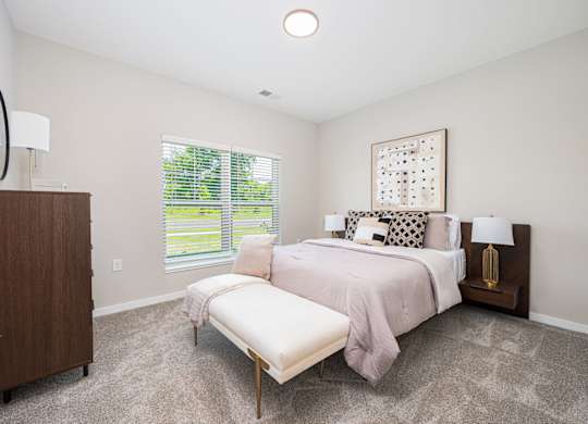 A bedroom with a large bed and a window with blinds.