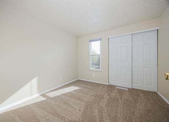 A room with a carpeted floor and a white door.