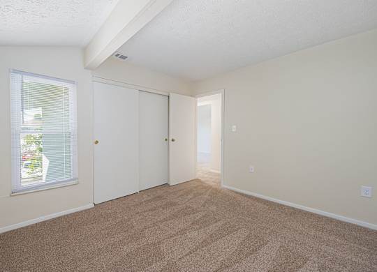 a spacious living room with carpet and a door to a bedroom