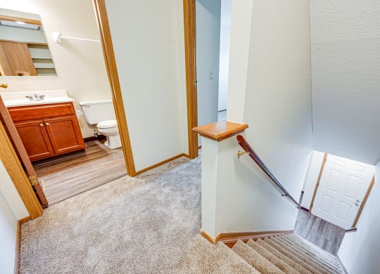 the landing of a staircase in a home with a bathroom and a toilet