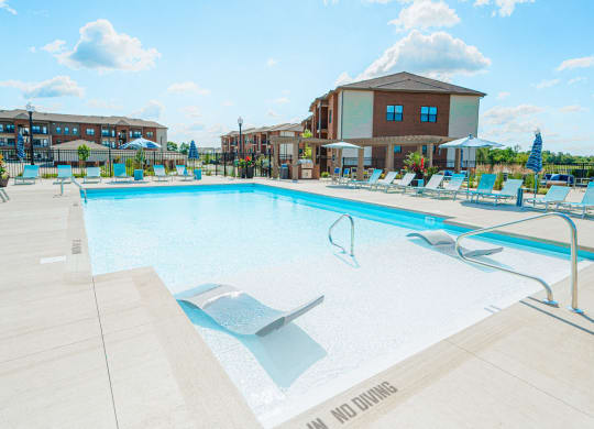 a swimming pool with chairs and a building in the background