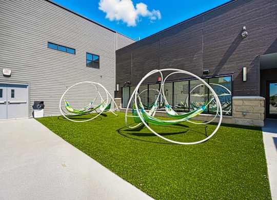 A white and green sculpture sits on a green lawn in front of a building.