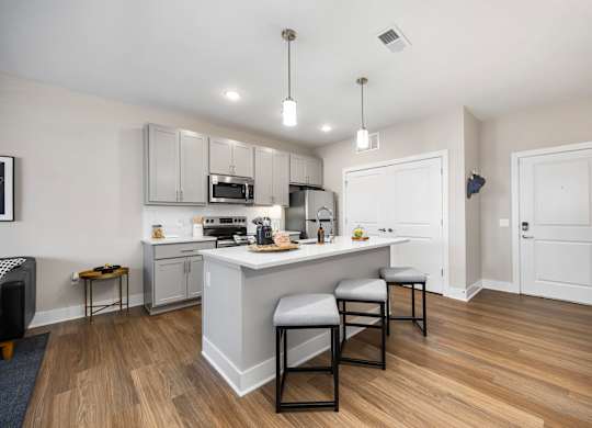 A kitchen with a white island and black chairs.