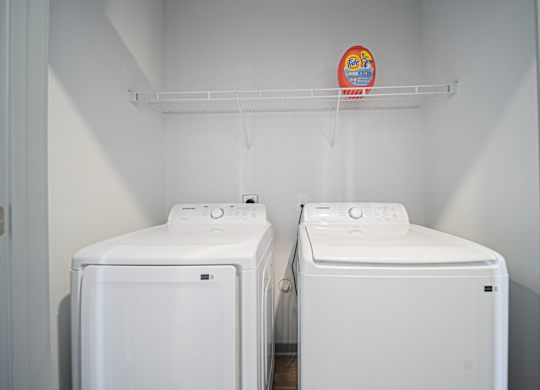 Two white washing machines in a laundry room.