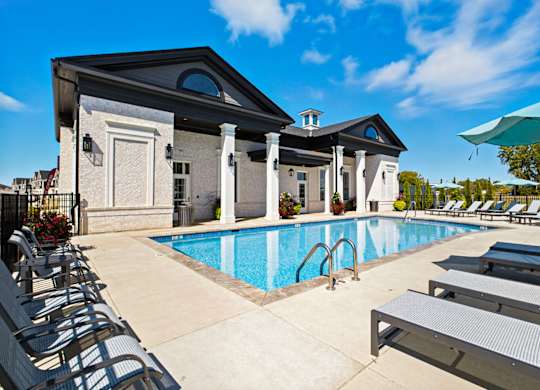 A pool area with sun loungers and a building in the background.