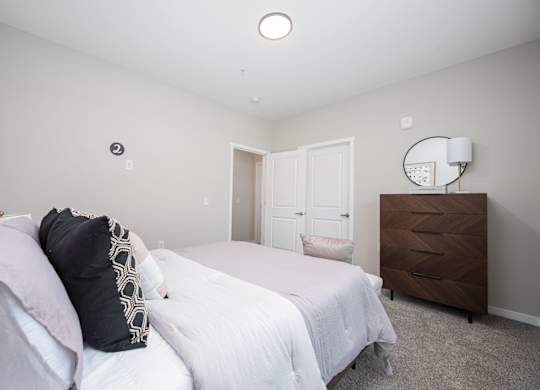 A bedroom with a bed, dresser, and mirror.