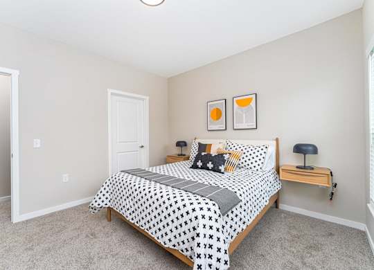 A bedroom with a bed, nightstand, and two pictures on the wall.