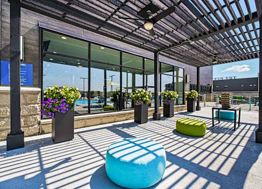 A sunny day at the outdoor seating area of a modern building with a blue bench and a yellow ottoman.