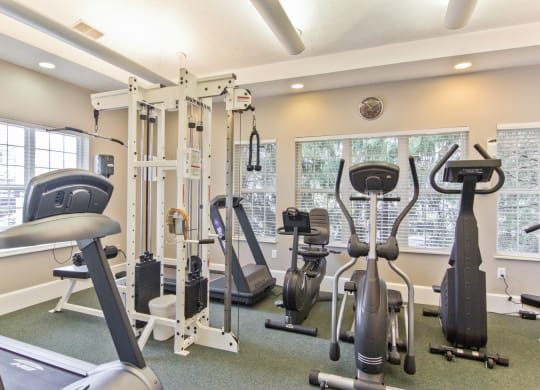 a gym with cardio machines and weights at the enclave apartments