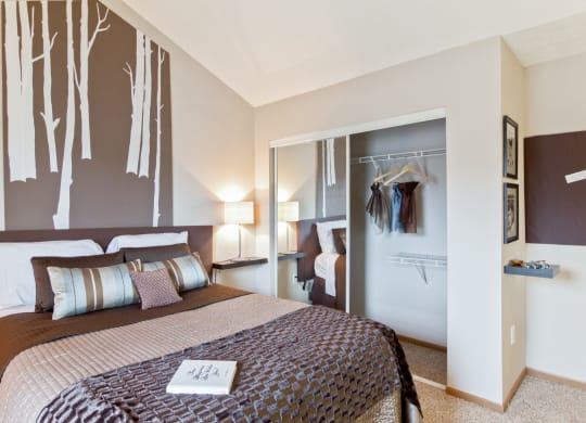 a bedroom with a bed and a closet with clothes hanging on the wall