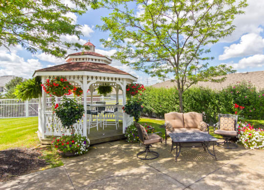 a gazebo on a patio with chairs and a table