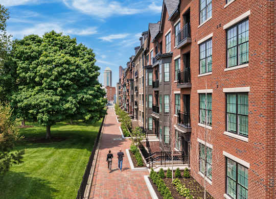 people walking down a sidewalk in front of apartments