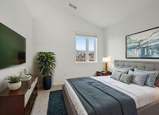 A bedroom with a large bed and a flat screen TV mounted on the wall.
