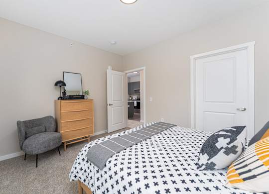 A bedroom with a bed, chair, and dresser.