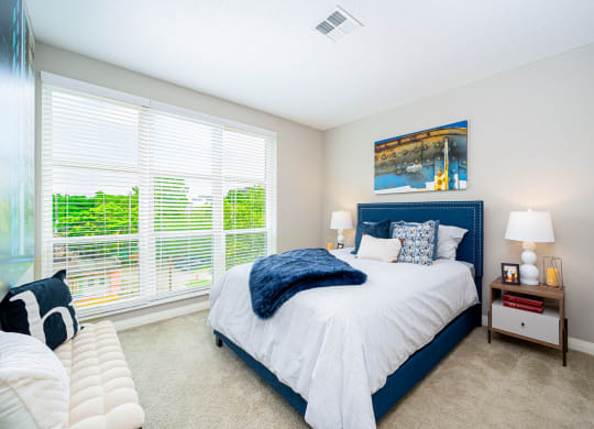 a bedroom with a blue and white bed and large windows
