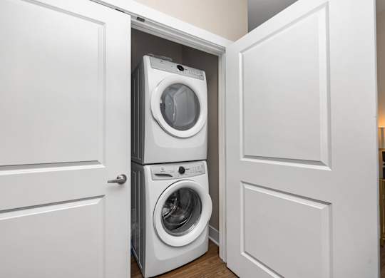 A white washing machine is in a white cabinet.