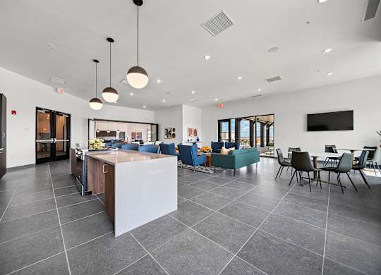 A modern kitchen with a large island and a dining area with chairs.