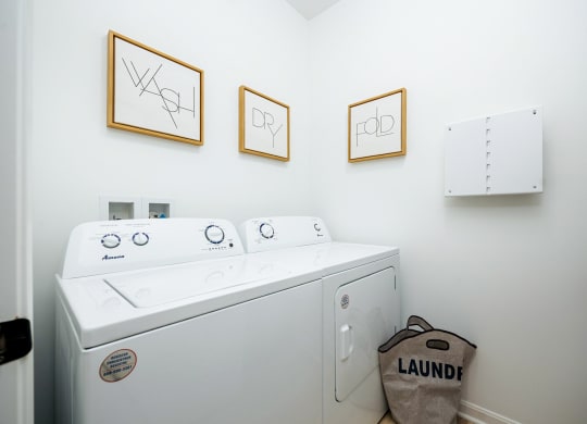 a washer and dryer in a laundry room with three pictures on the wall