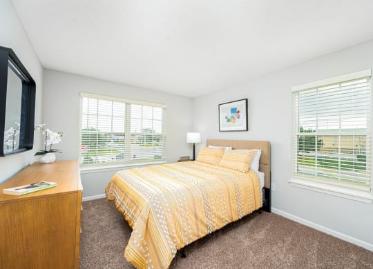 a bedroom with a yellow bed and two windows