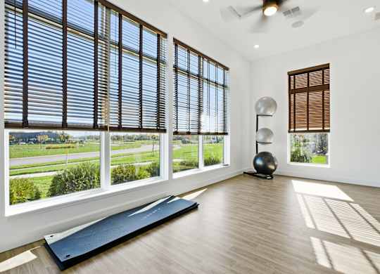 A room with a large window and a yoga mat on the floor.