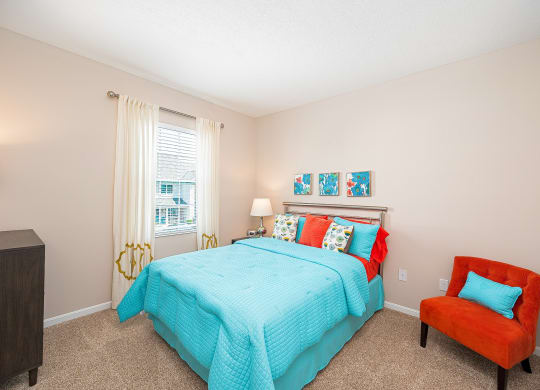 a bedroom with a bed and a chair and a window