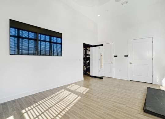 A room with a large window, wooden floors, and white walls.
