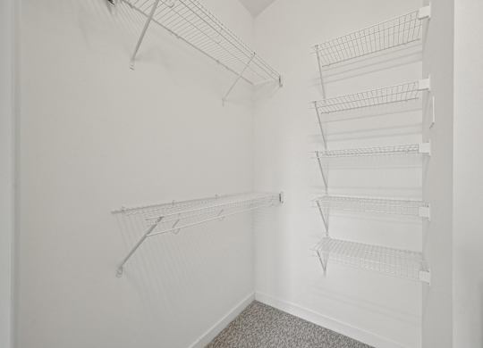 Empty white closet with shelves and hangers.